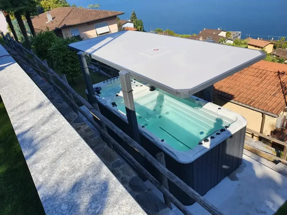 PassionSpa Spirit Deep swim spa – grey finish, white cover, black massage jets, stone patio, by the sea