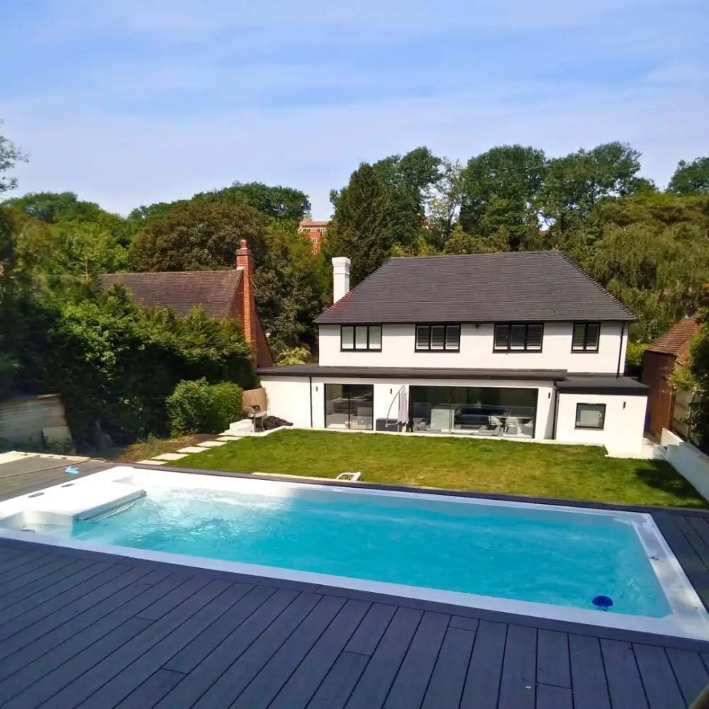 PassionSpa Turbine 6 Grand Swim Spa med klarblått vatten och vit kant på grå trädäck