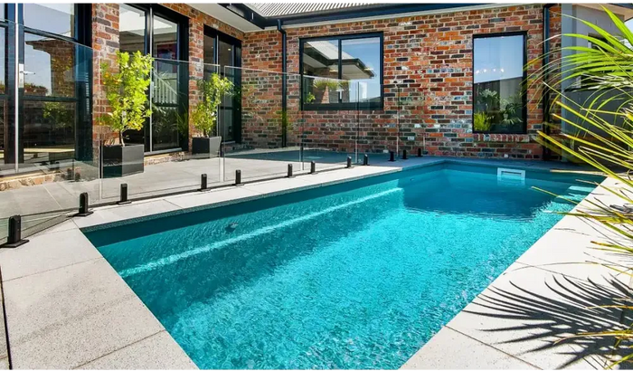 Rectangular pool – clear blue water, neatly trimmed hedges and stone paving