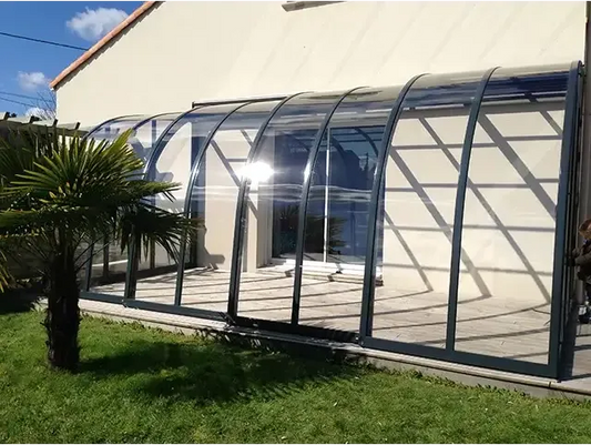 Patio enclosure – black frame, curved roof with clear panels, for a pool and patio