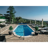 Glasfiberpool Barbados med klar blå poolvatten, stenplattor och krukväxter