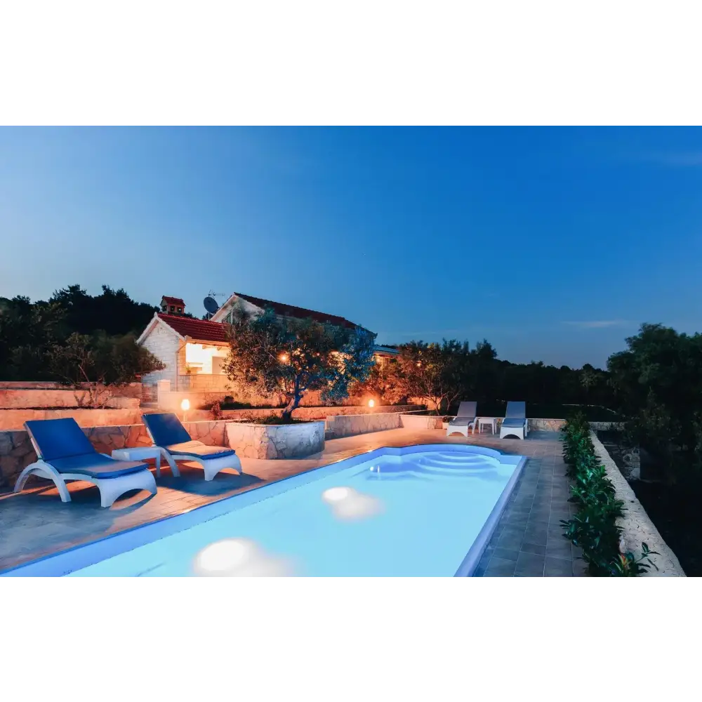 Glasfiberpool Haiti med avrundad trappa vid trädgårdspool i skymning