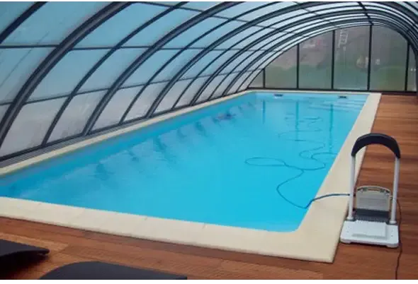 Blå inomhuspool med genomskinligt valv och trädeck för glasfiberpool Jamaika 25x3 75x1 50m