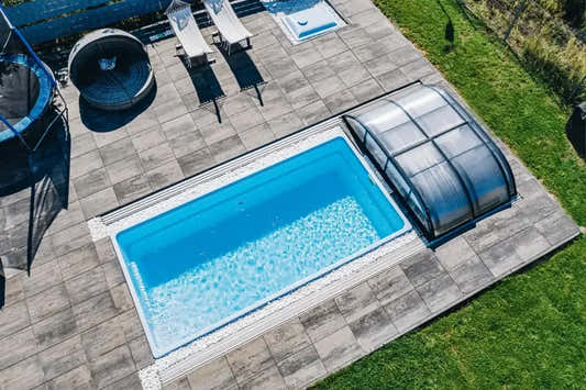 Papeete fibreglass pool – clear blue water, transparent cover, grey stone paving Papeete fibreglass pool – clear blue water, transparent cover, grey stone paving