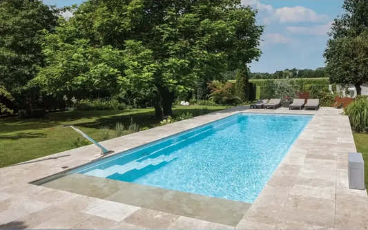 Leisurepools Definitive pool – high waterline, rectangular pool, clear blue water, beige stone paving
