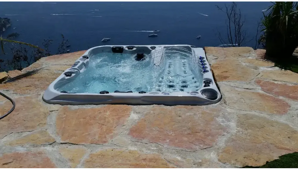 PassionSpa Euphoria Mighty Wave hot tub – grey finish, black massage jets, stone patio, by the sea
