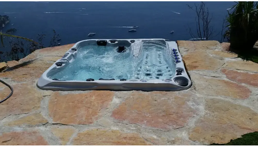 PassionSpa Euphoria Mighty Wave hot tub – grey finish, black massage jets, stone patio, by the sea