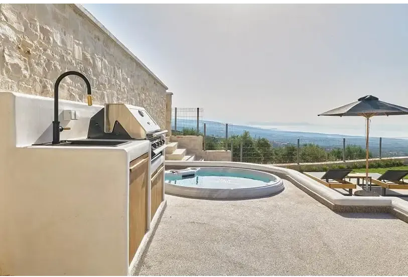 PassionSpa Recharge hot tub – Pure Collection, beige stone outdoor kitchen with a black tap and stainless steel barbecue