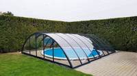Classic pool enclosure in anthracite with a curved shape and clear polycarbonate panels in a garden.
