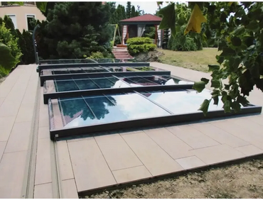 Pooltak Mästare Plus med modern glasdesign och svart ram över kaklat uteplats