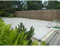 Grey pool cover including a manual operating unit – metal frame, green plants in the foreground